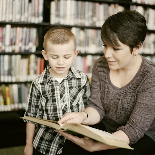 A woman reading a book with a young boy