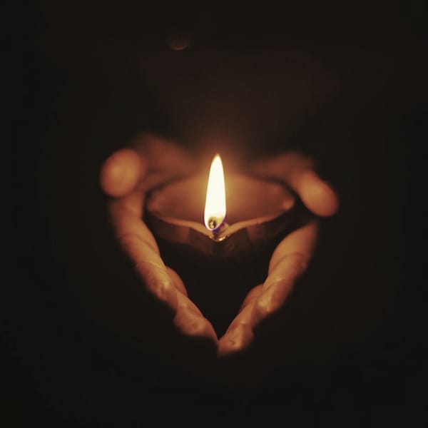 Hands cupping a lit oil lamp